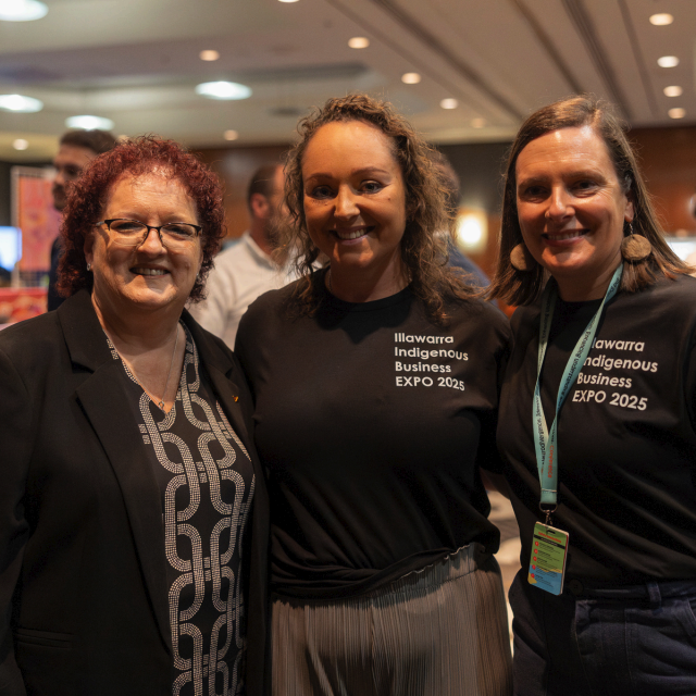 Three women smiling together at the Illawarra Indigenous Business Expo 2025, two wearing event t-shirts.
